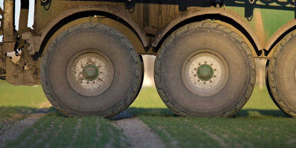 Närbild på stora maskinhjul som packar marken under.