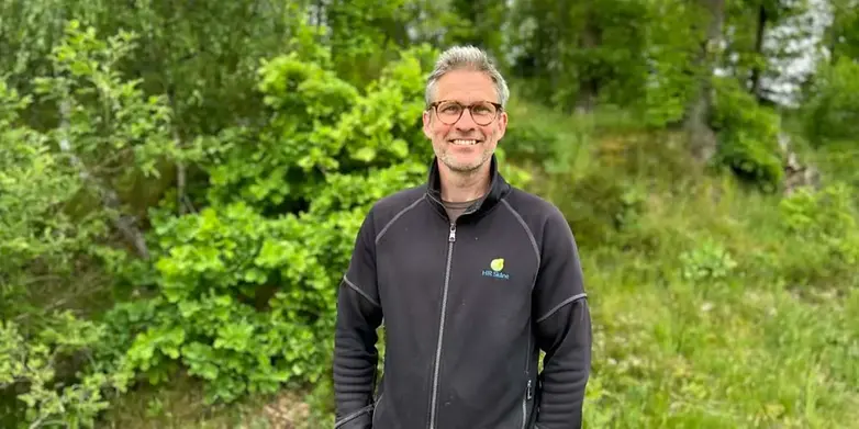 Man som står framför grönt buskage
